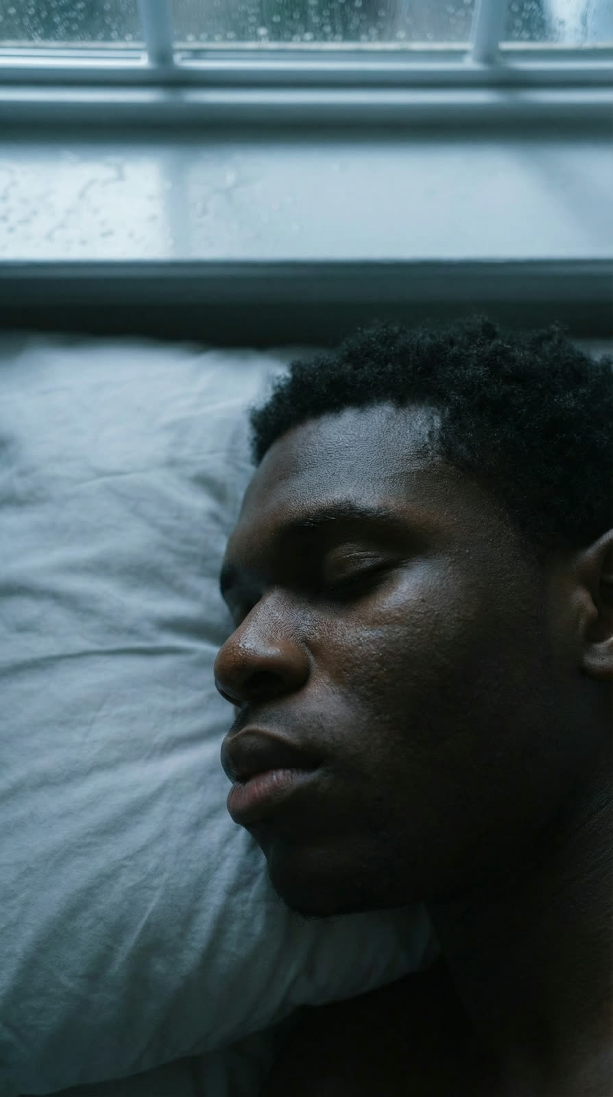 The athlete on his side on the pillow, staring at nothing