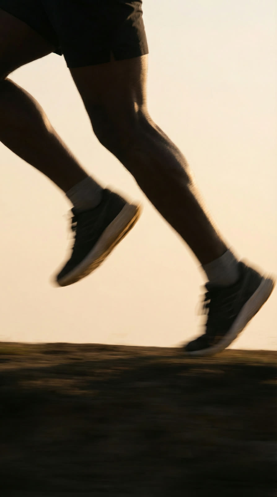 The athlete’s legs and shoes mid-stride on dirt