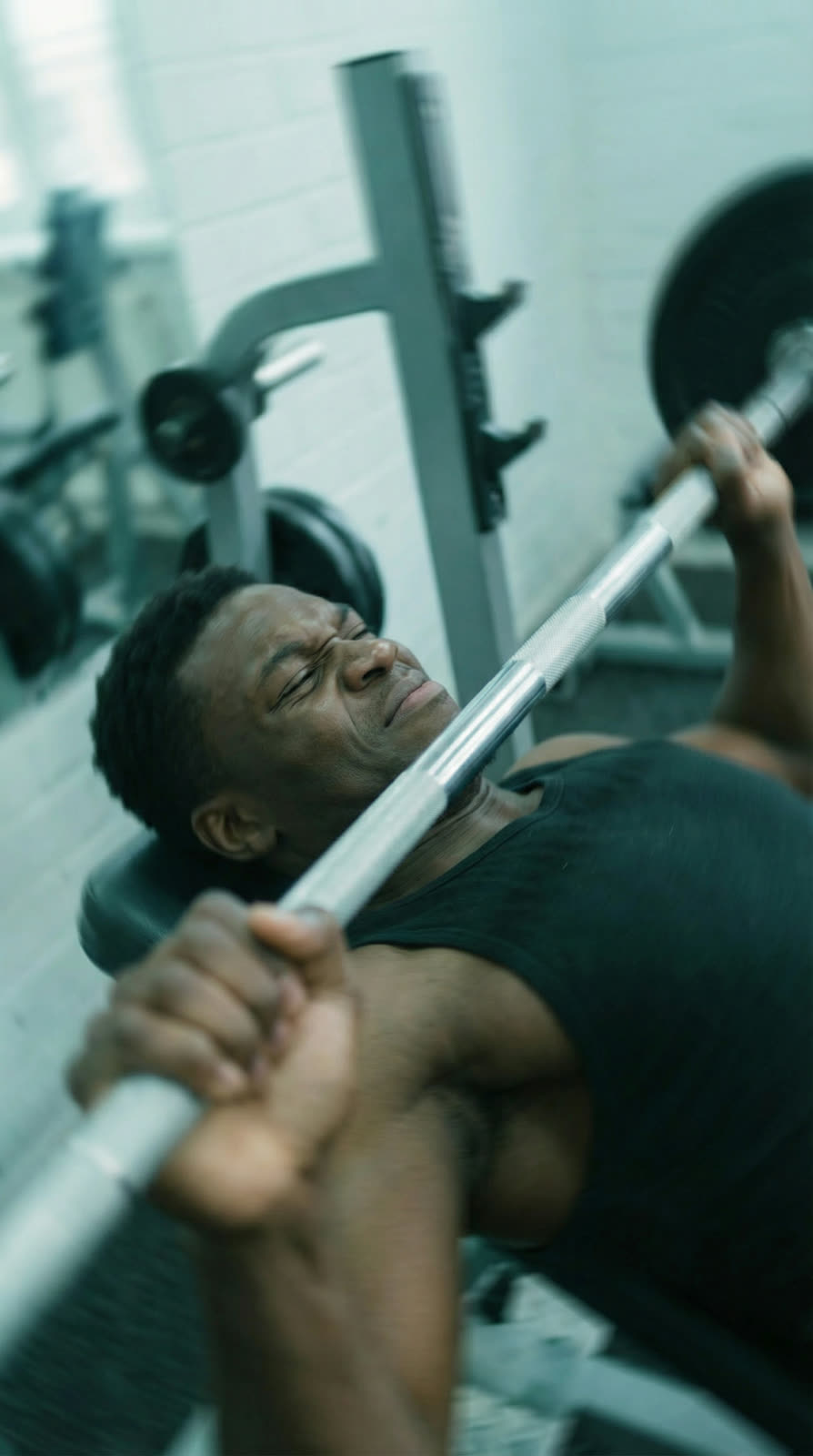 The athlete on the bench press, looking up with the bar in his hands